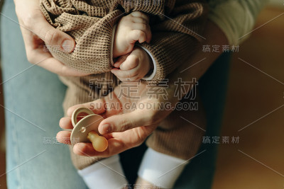 婴儿把奶嘴放在妈妈的怀里
