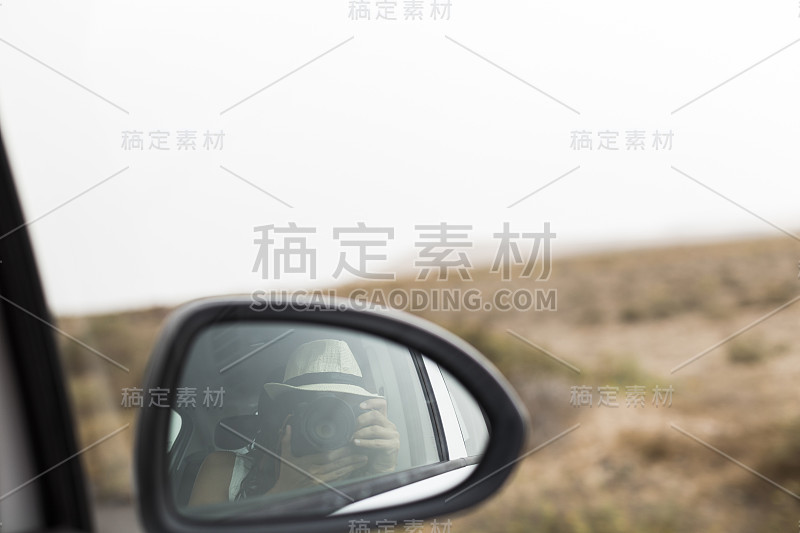 年轻女子从一辆汽车的后视镜拍照。夏天。生活方式