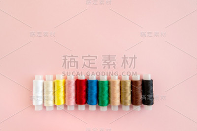 在粉红色背景上缝制衣服用的彩色线圈。