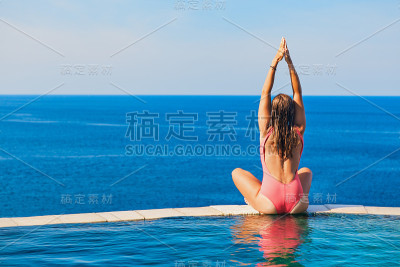 在无边泳池边的女人可以看到海景。