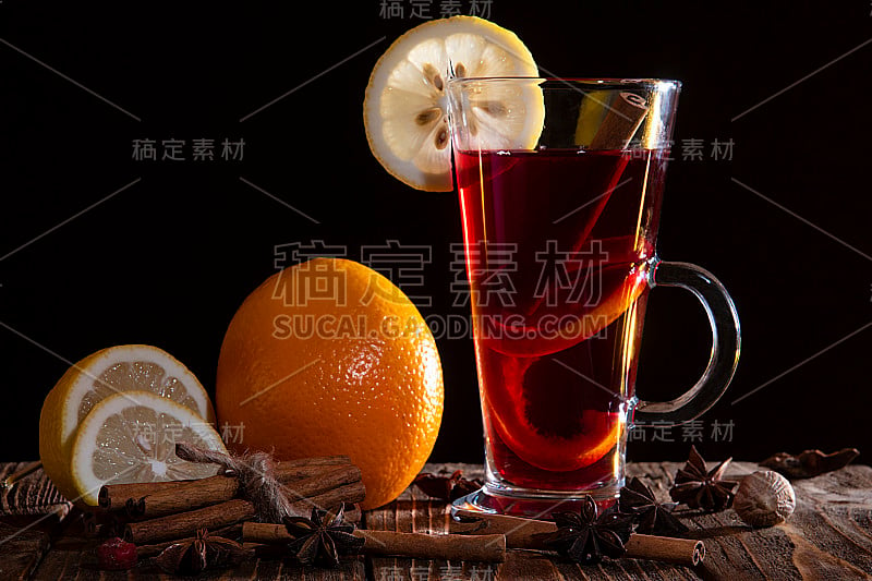 A glass of mulled wine with an orange peel and a s