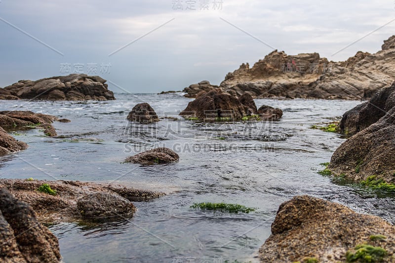 美丽的岩石景观与平静的大海和蓝色背景