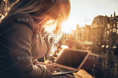 一个在日落时分用笔记本上网刷信用卡的女人