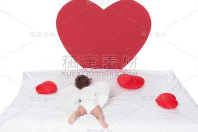 小丘比特带着翅膀躺在床上，心被孤立在白色