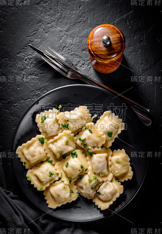 肉馅饺子-俄罗斯饺子，肉馅馄饨在黑色的盘子上，在深灰色的黑色石板的背景