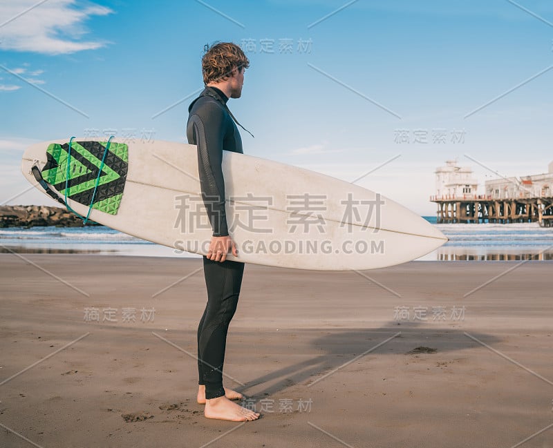 冲浪者拿着冲浪板站在海里。