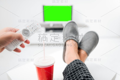在客厅的桌子上，男人一边喝着汽水，一边看电视。色度键绿色屏幕。