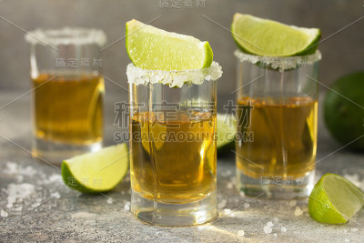黄金龙舌兰酒。墨西哥金龙舌兰酒与石灰和盐在石头轻混凝土工作台上。
