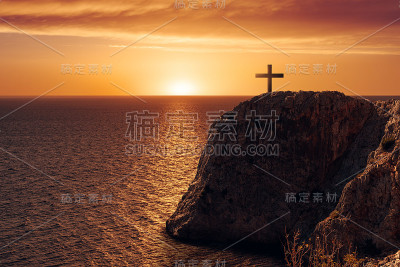 鸟瞰图十字架在悬崖边对着大海和日落。