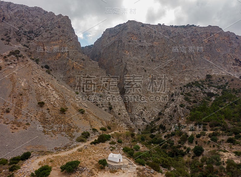 希腊一个巨大的岩石峡谷背景上的白色小教堂，航拍照片