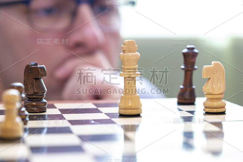 一个人若有所思地看着棋子。国际象棋的游戏。棋盘上的棋子。