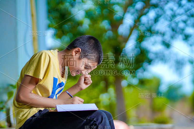 印度一名男孩手持手机，使用手机应用程序进行远程学习，观看在线课程，视频呼叫在应用程序中做笔记，在家学