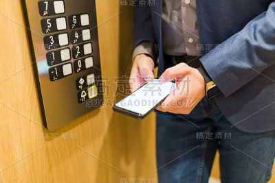 近距离的现代男人的手拿着空白屏幕智能手机在电梯里。