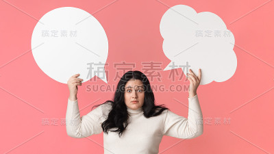 困惑的肥胖女孩在她的头上举着两个空的演讲泡泡