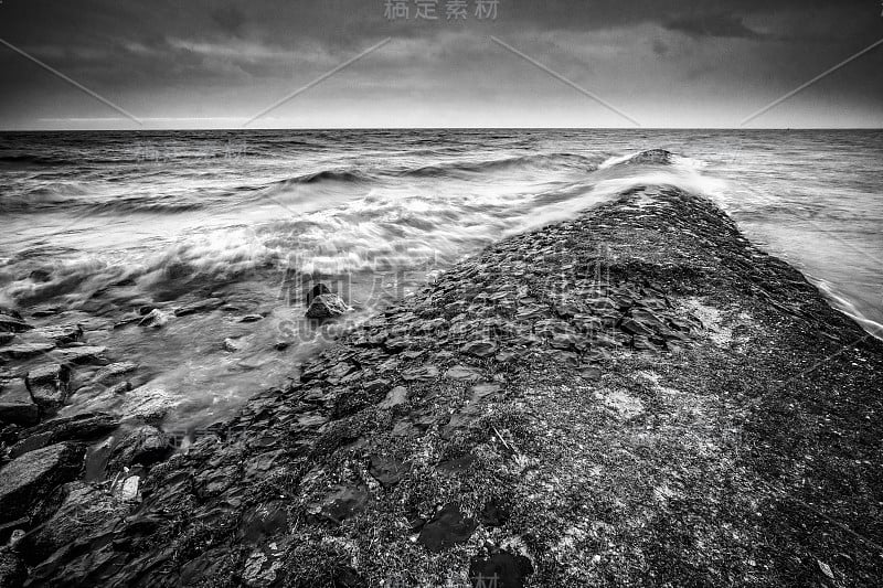 有暴风雨的天气，湖面上有乌云，海岸线上有暴风雨的波涛