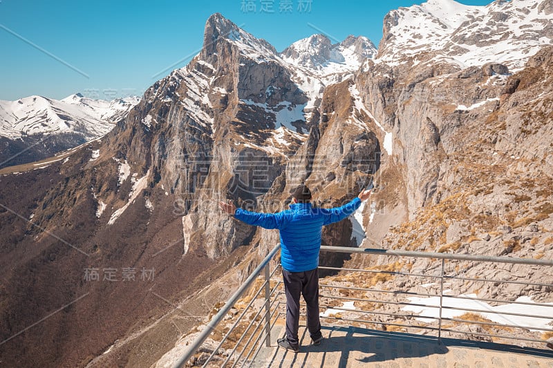 一个人的手在空中的一个观点，与覆盖着雪的山。一个男人看着美丽的群山全景。国家公园欧洲的山峰。Fuen