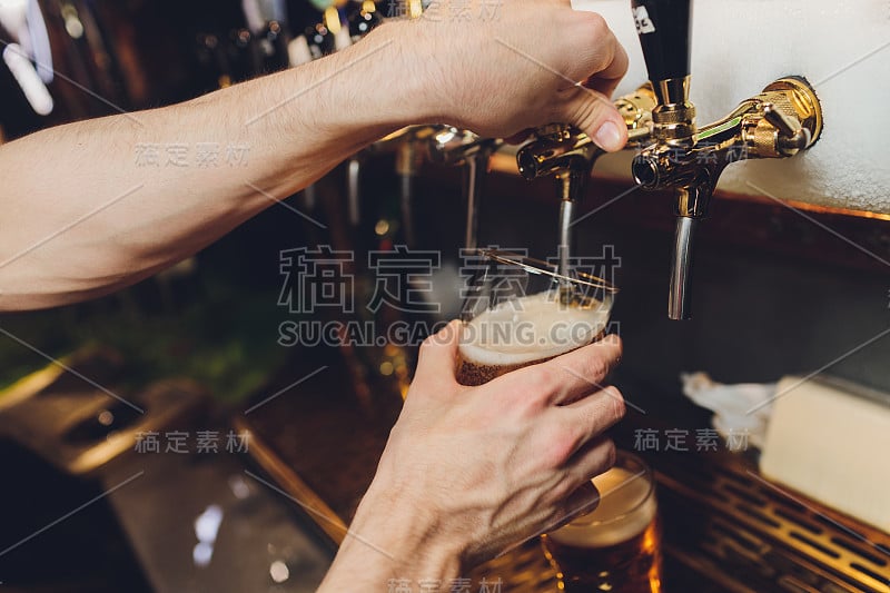 特写的酒吧服务员的手在啤酒龙头倒大桶装啤酒。