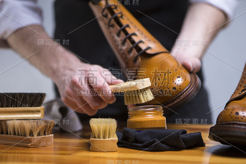 极端近距离的男人的手清洁与特殊的配件，鞋蜡和工具豪华小牛皮布洛克鞋。水平的形象定位