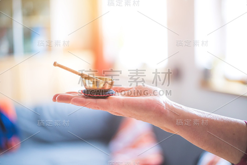 婴儿唱碗:女人手里的小金属唱碗。模糊的背景。