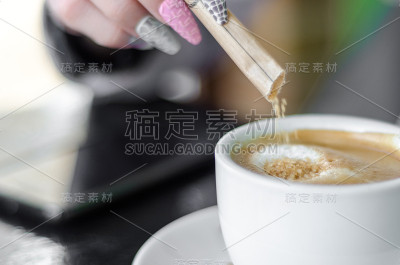 女人用手把糖倒进咖啡里
