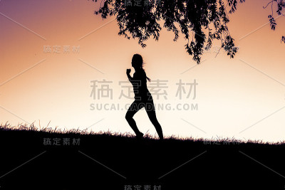 夕阳下女人在户外跑步的剪影——健身训练
