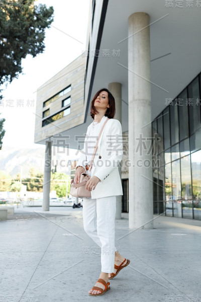 美丽的中年千禧时尚潮女人摆姿势，穿着白色的衣服。成功商业区，复制空间