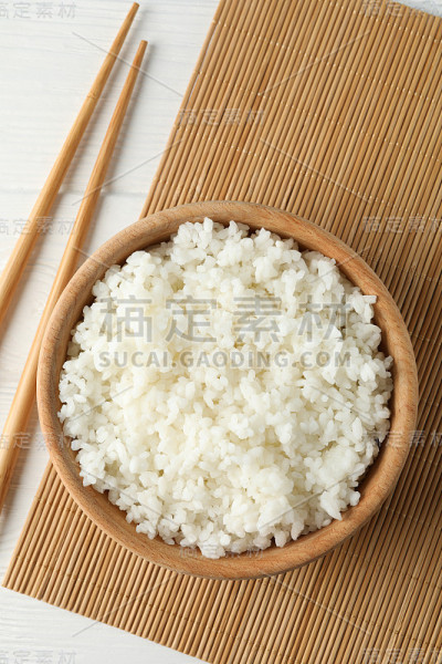 碗与煮米饭和筷子在木背景，俯视图