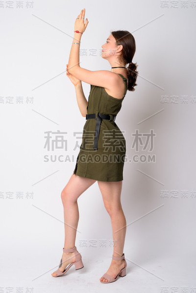 年轻美丽的女人举起手臂摆姿势的全身照侧面视图