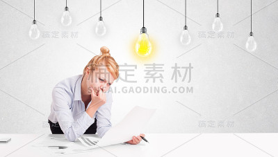 女商人坐在桌子前摆弄着点子灯泡