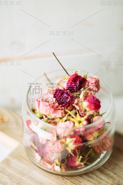 黄麻背景上的玻璃瓶中的干玫瑰花蕾