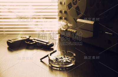 用于窃听的卷筒磁带录音机。克格勃间谍的谈话。黑色枪附近。烟灰缸里有一支香烟。黑白照片。