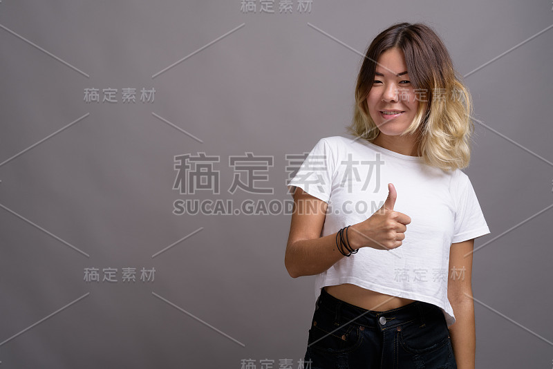 一名年轻的亚洲女子穿着白色衬衫，背景是灰色