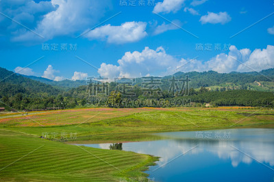 宁静的山景与绿色的草地，清澈的湖水和蓝天背景。山绿色山谷景观与湖泊，绿色的田野和清澈的蓝天背景。