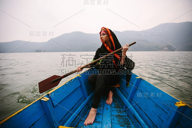 淡妆长红发的女子坐在山湖中的小船上