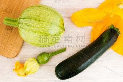 木桌上放着绿色的西葫芦和花朵