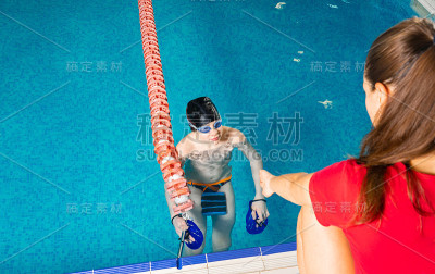 水中女教练在室内游泳池给青春期前的男孩上游泳课