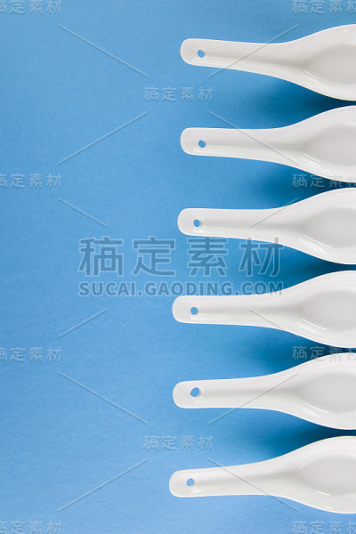 白色亚洲风格的勺子排列在几何图案的蓝色背景