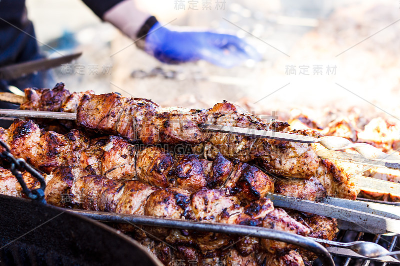 在露天金属烤架上烤羊肉串的过程。烤架上烤烤肉串。腌肉。