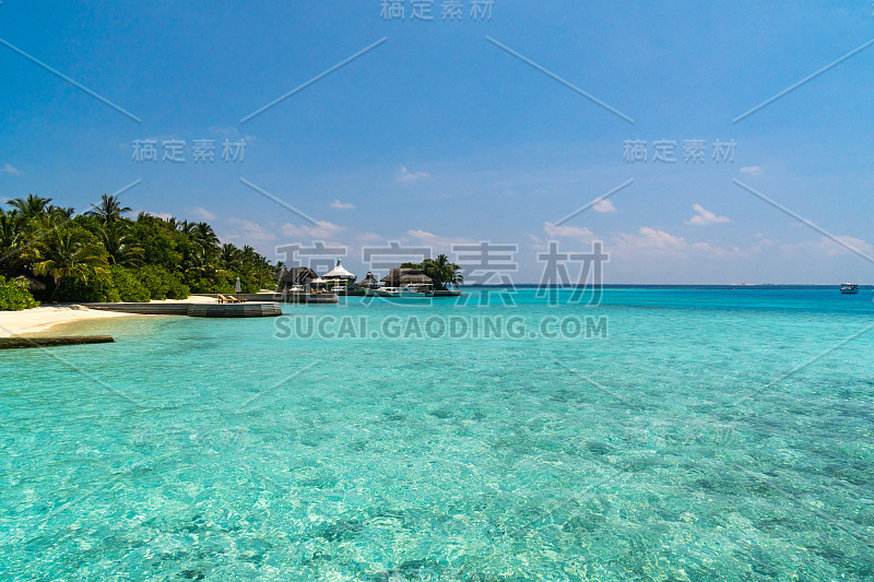 热带马尔代夫岛背景。有游艇的码头，碧绿的泻湖水域和晴朗夏日的蓝天。