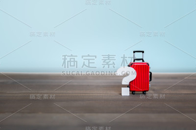 木制桌子上的红色行李箱上的问号，旅行问题概念