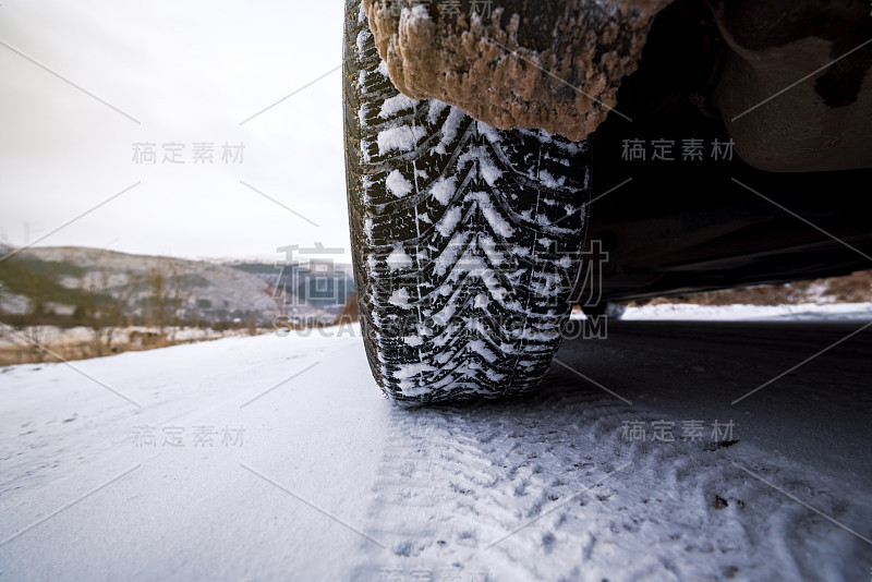 汽车轮胎在被雪覆盖的冬季道路上行驶。