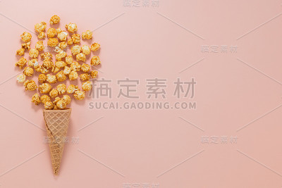 焦糖爆米花在华夫蛋筒在粉红色的背景俯视图
