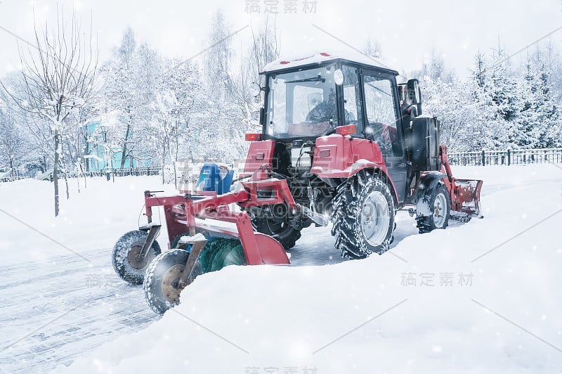 一辆红色的旧拖拉机在暴风雪中清理街道上的积雪。冬天的街道清洁