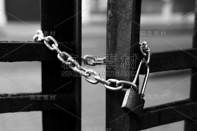 黑色和白色的铁链和锁在铁栅栏上。
