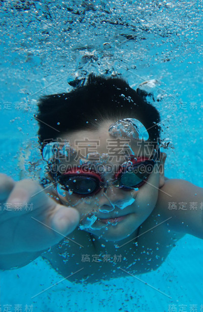 快乐的亚洲小孩在水下戴着泳镜