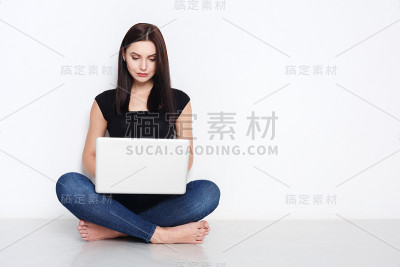一个坐在演播室地板上用笔记本电脑的女人