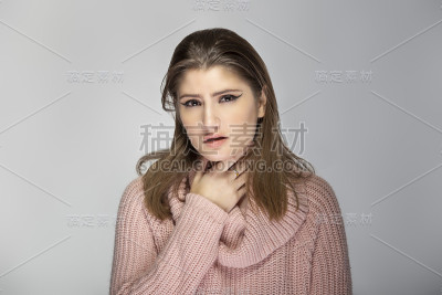 一个年轻女性的肖像，穿着粉红色的毛衣，喉咙痛