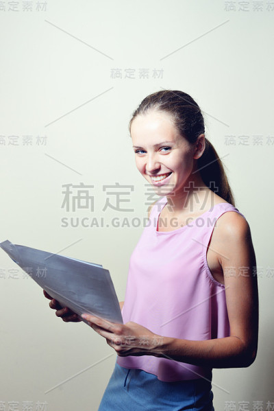 年轻的女商人坐在办公室里看报纸