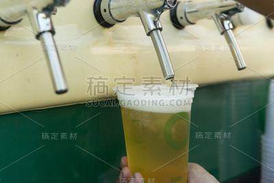 酒保将新鲜啤酒倒入塑料杯中。