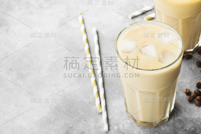 在灰色的背景下，用高脚杯盛着加牛奶的冰咖啡。副本的空间。食品的背景